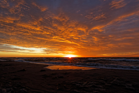 Cloudy sky during sunset. View of the sea absorbing the sun.の写真素材