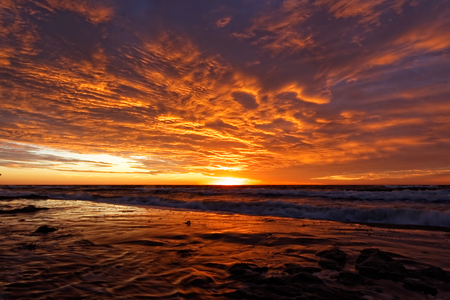 Cloudy sky during sunset. View of the sea absorbing the sun.の写真素材