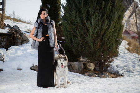 Serious woman in a fur hat with a Husky dogの写真素材