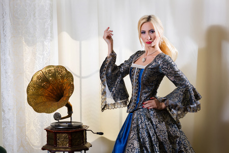 Girl in medieval dress standing next to a gramophoneの写真素材