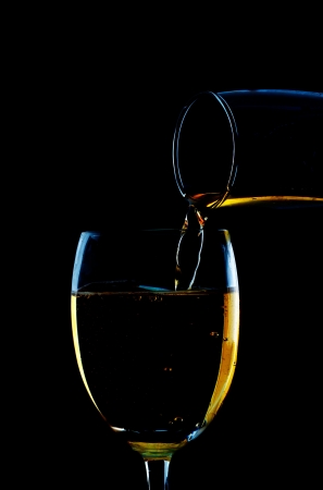 pouring white wine on a black background の写真素材