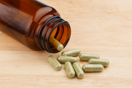 Herb capsule spilling out of a bottleの写真素材