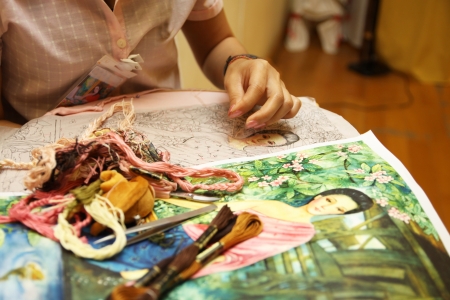 Woman hand embroiders with a needle and a thread 
