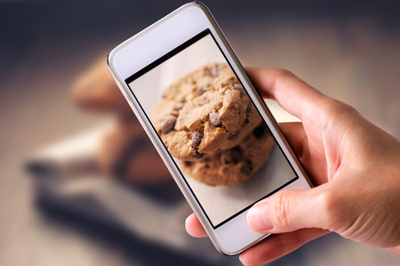 using mobile phone to take photos of Chocolate Cookies on white napkin and wooden background