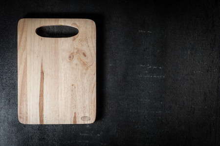Wooden cutting board on black stone background