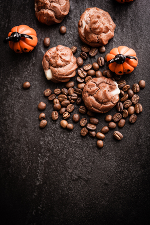 Eclairs and coffee beans with halloween decoration on black backgroundの写真素材
