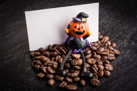 Red gift box and halloween toy decorate with roasted coffee beans on dark  background, can be used as a backgroundの写真素材
