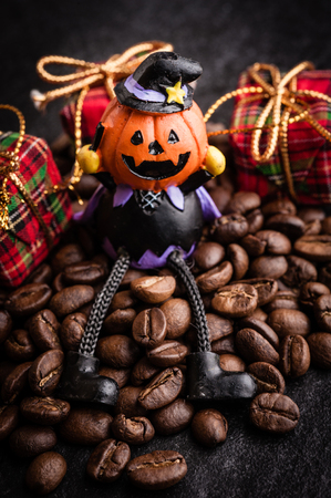 Red gift box and halloween toy decorate with roasted coffee beans on dark  background, can be used as a backgroundの写真素材