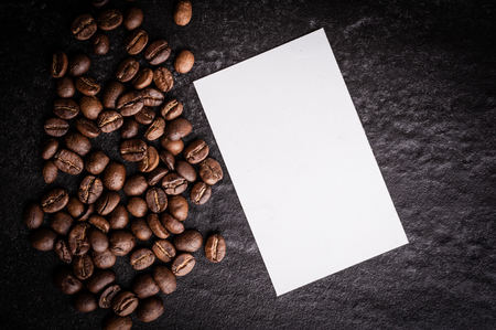 roasted coffee beans with blank paper on dark background, can be used as a backgroundの写真素材