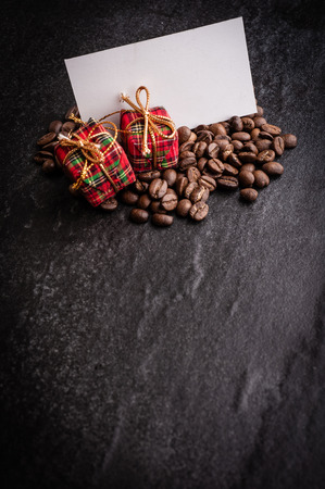Red gift box and blank paper with roasted coffee beans on dark  background, can be used as a backgroundの写真素材