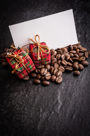 Red gift box and blank paper with roasted coffee beans on dark  background, can be used as a backgroundの写真素材