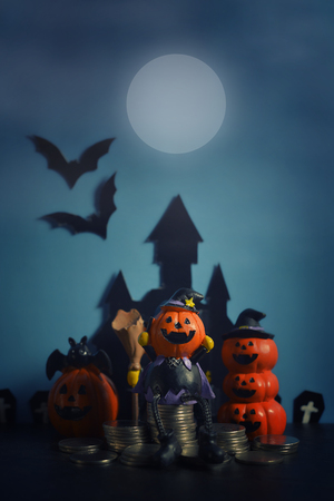 Halloween pumpkins jack-o-lantern with money coin stack growing business on dark blue background. Happy Halloween.の写真素材