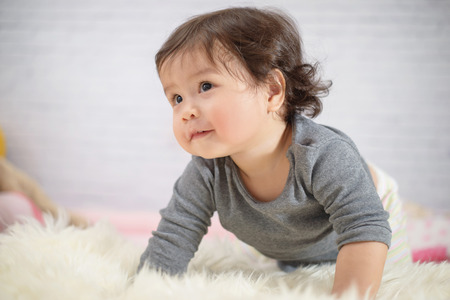 Sweet Beautiful baby girl playing on beautiful white furry.Newborn baby concept.