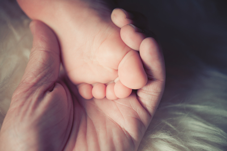 Mother hold small bare feet of a little baby girl or boy. Sleeping newborn child. Bare feet of a...