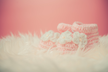 Close up Baby girl knitted shoes on white blanket background.Happy new year greeting card with copy-space. New born celebration holiday concept.の写真素材