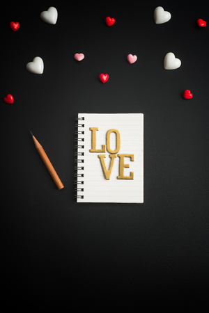 Flat view of blank notepads in the centre of valentines hearts on black color background with copy space. Symbol of love. Happy Valentines Day background.Saint Valentine's Day concept. Can be used for celebrations valentines day.の写真素材
