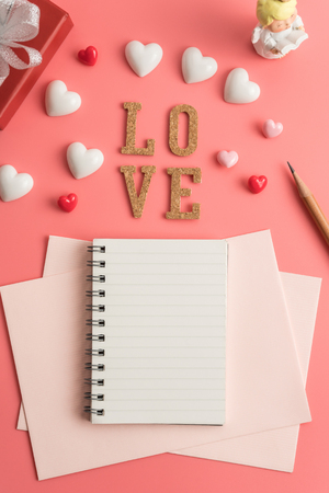 Flat view of notepads in the centre of valentines hearts and decoration on pink background with copy space.の写真素材