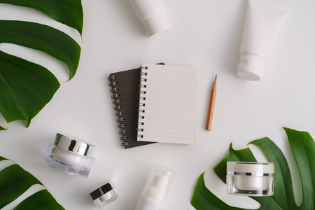 White cosmetic products and green leaves on white background. Natural beauty products for branding mock-up concept.の写真素材