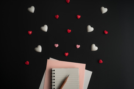 Flat view of notepads with valentines hearts and decoration on dark background with copy space.の写真素材