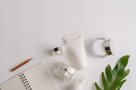 White cosmetic products and green leaves on white background. Natural beauty products for branding mock-up concept.の写真素材