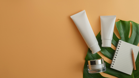 White cosmetic products and green leaves on color background. Natural beauty product for branding mock-up concept.の写真素材