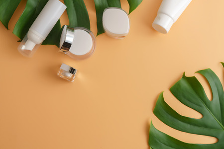 White cosmetic products and green leaves on color background. Natural beauty product for branding mock-up concept.の写真素材