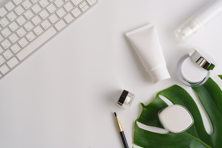 White cosmetic products and green leaves on white background. Natural beauty products for branding mock-up concept.の写真素材