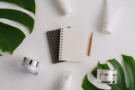 White cosmetic products and green leaves on white background. Natural beauty products for branding mock-up concept.の写真素材