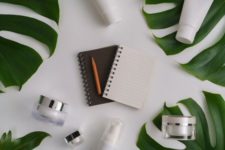 White cosmetic products and green leaves on white background. Natural beauty products for branding mock-up concept.の写真素材