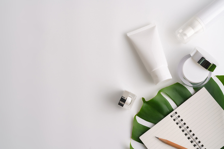 White cosmetic products and green leaves on white background. Natural beauty products for branding mock-up concept.の写真素材