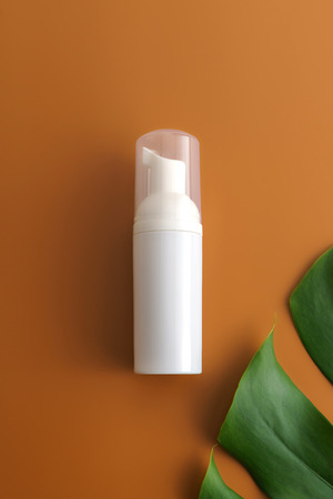 White cosmetic products and green leaves on white background. Natural beauty products for branding mock-up concept.の写真素材