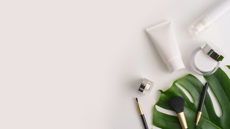 White cosmetic products and green leaves on white background. Natural beauty products for branding mock-up concept.の写真素材