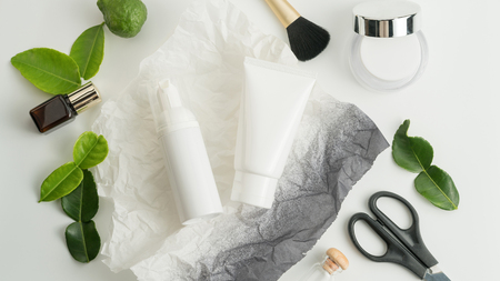 White cosmetic products and green leaves on white background. Natural beauty products for branding mock-up concept.の写真素材