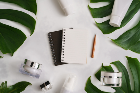 White cosmetic products and green leaves on white background. Natural beauty products for branding mock-up concept.の写真素材