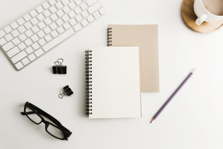 White office desk table with blank notebook, computer, supplies and coffee cup. Top view with copy space. Flat lay.の写真素材
