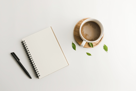 White office desk table with blank notebook, computer, supplies and coffee cup. Top view with copy space. Flat lay.の写真素材