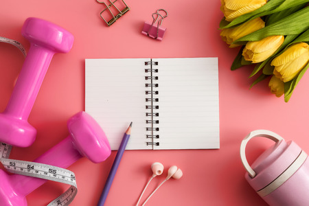 Styled stock photography of fitness equipment dumbbells notepad pencil and earphone on pink background. Flat lay.の写真素材