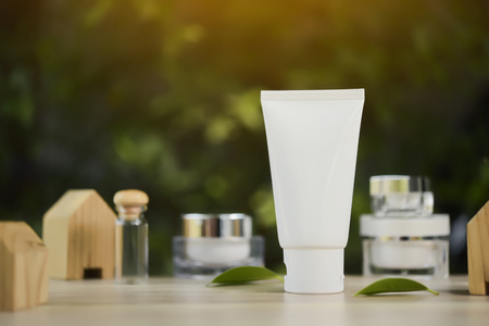 White cosmetic products and green leaves on white background. Natural beauty products for branding mock-up concept.の写真素材