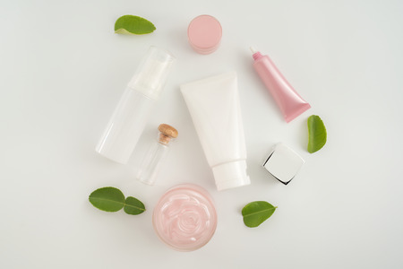 White cosmetic products and green leaves on white background. Natural beauty blank label for branding mockup concept.の写真素材