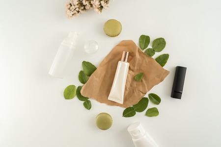 White cosmetic products and green leaves on white background. Natural beauty blank label for branding mockup concept.の写真素材