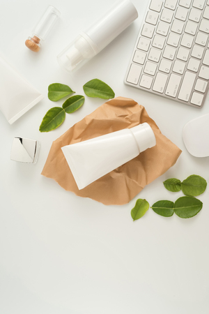 White cosmetic products and green leaves on white background. Natural beauty blank label for branding mockup concept.の写真素材
