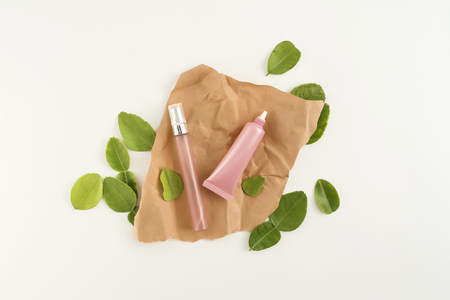 Pink cosmetic products with green leaves on white background. Natural beauty blank label for branding mockup concept.の写真素材