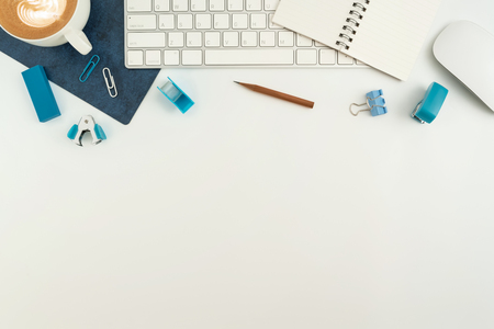 Flat lay, top view office table desk. Work space with blank note book, keyboard, blue office supplies and coffee cup on white background.の写真素材