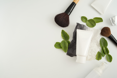 White cosmetic products and green leaves on white background. Natural beauty blank label for branding mockup concept.の写真素材