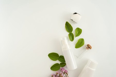 White cosmetic products and green leaves on white background. Natural beauty blank label for branding mockup concept.の写真素材