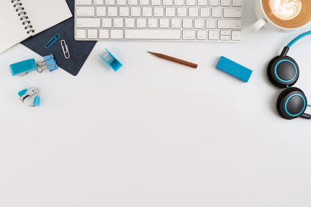 Flat lay, top view office table desk. Work space with blank note book, keyboard, blue office supplies and coffee cup on white background.の写真素材