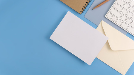 Flat lay, top view office table desk. Workspace with blank note book, keyboard, office supplies and coffee cup on light blue background.の写真素材