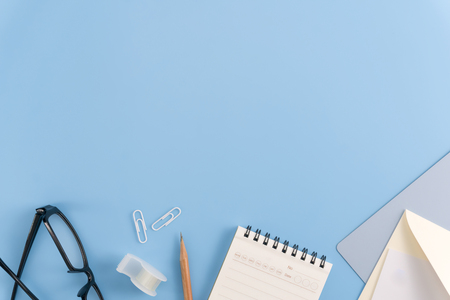 Flat lay, top view office table desk. Workspace with blank note book, keyboard, office supplies and coffee cup on light blue background.の写真素材