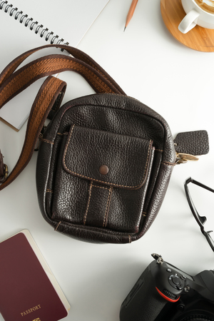 Traveler accessories, leather bag, coffee cup, notepad, camera  and passport on white background with copy space.Travel vacation concept. Flat lay, top view.の写真素材