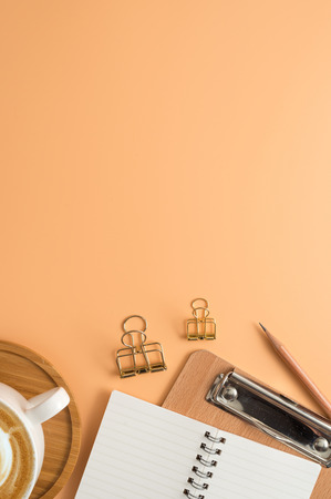 Flat lay, top view office table desk. Workspace with blank note book, keyboard, office supplies  and coffee cup on color background.の写真素材